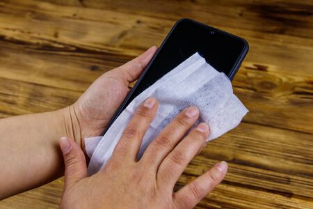 Woman hand cleaning smartphone screen with a wet wipeの写真素材