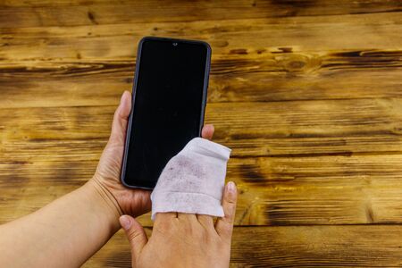 Woman hand cleaning smartphone screen with a wet wipeの写真素材