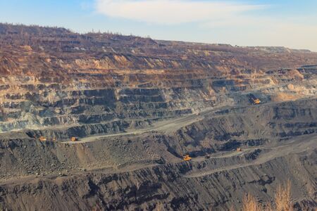 Huge iron ore quarry with working dump trucks and excavators