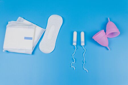 Sanitary pad, tampons and menstrual cup on blue background. Top view. Concept of critical days, menstruation, feminine hygieneの写真素材