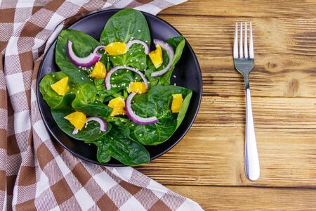 Tasty salad with spinach, orange, red onion and sesame seeds on wooden table. Top view. Healthy food or vegetarian conceptの写真素材