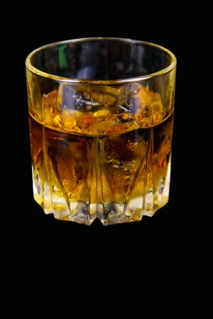 Glass of whiskey with ice on a black backgroundの写真素材