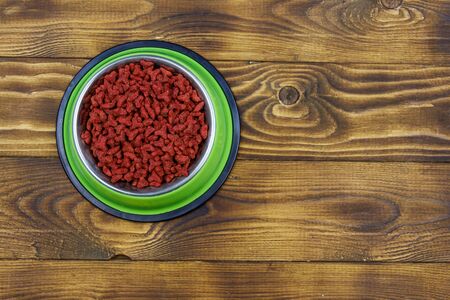 Dry food for cat or dog in bowl on wooden background. Pet food on wood surface. Top view, copy spaceの写真素材