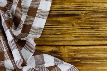 Brown folded checkered napkin on rustic wooden kitchen table. Top view, copy spaceの写真素材