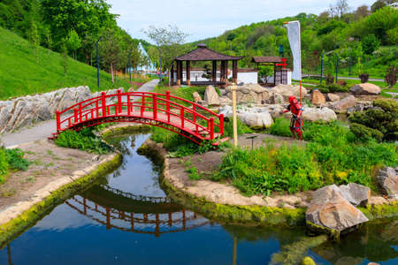 Red bridge and gazebo by a pond in Japanese gardenの写真素材