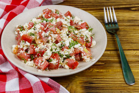 Tasty salad of tomato, cottage cheese, dill and olive oil on wooden tableの写真素材