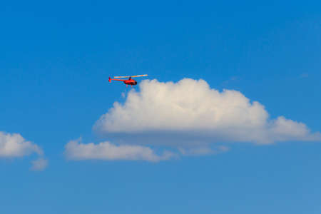 Flying orange helicopter in blue skyの写真素材