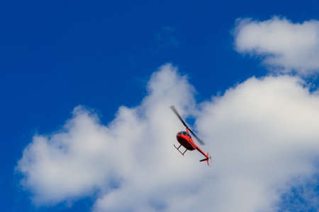 Flying orange helicopter in blue sky