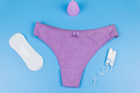 Women's panties with menstrual cups, sanitary pads and tampons on pastel blue background. Top view. Concept of critical days, menstruation, feminine hygieneの写真素材