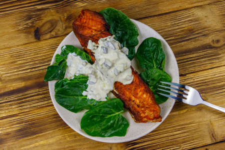 Grilled salmon fillet with spinach and tartare sauce on wooden table. Top viewの写真素材