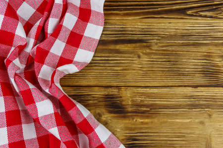 Red folded checkered napkin on rustic wooden kitchen table. Top view, copy spaceの写真素材