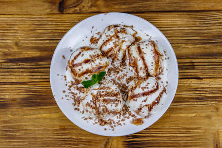 Vanilla ice cream with chocolate topping in white plate on a wooden table. Top viewの写真素材