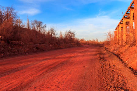 Red dirt road polluted with iron ore near iron ore quarry in Kryvyi Rih, Ukraineの写真素材