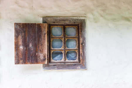 Old wooden window with shutter in old traditional ukrainian clay houseの写真素材