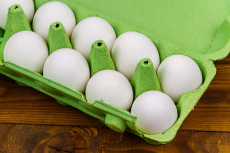 Raw chicken eggs in cardboard egg box on wooden table