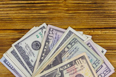 Stack of different us dollars bills on wooden deskの写真素材