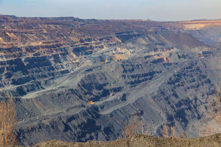Huge iron ore quarry with working dump trucks and excavators