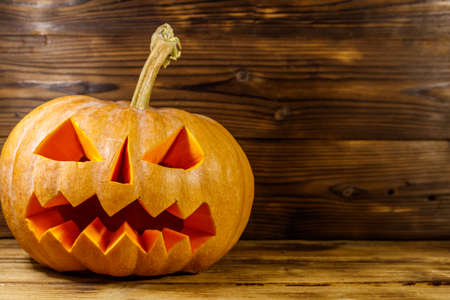Spooky Halloween pumpkin jack-o-lantern on a wooden backgroundの写真素材
