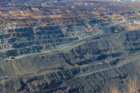 Huge iron ore quarry with working dump trucks and excavatorsの写真素材