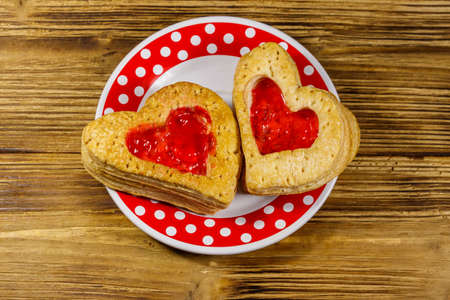 Heart shaped puff cookies with jam on a wooden table. Top view. Dessert on Valentine`s Dayの写真素材