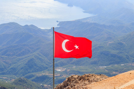 Waving flag of Turkey against mountains and seaの写真素材