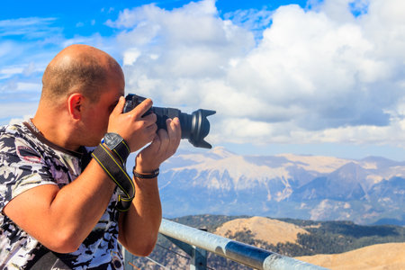 Travel photographer man with professional camera taking photos of on a top of Tahtali mountain near...
