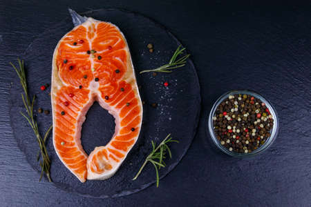 Raw salmon steak with spices on black slate. Top viewの写真素材