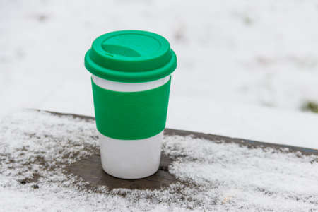 Cup of coffee on a snow covered table at winterの写真素材