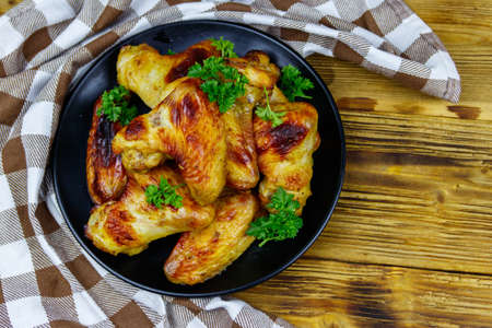 Baked chicken wings on a wooden table. Top view