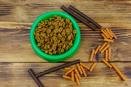 Dog delicacy food and feed in green plastic bowl on wooden background. Top view. Dog care conceptの写真素材