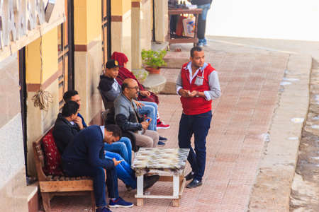 Cairo, Egypt - December 8, 2018: Unknown people spending time on a bench near a houseのeditorial素材