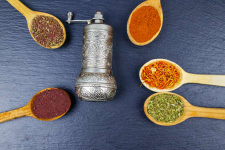 Set of different aromatic spices and spice mill on black slate. Top viewの写真素材