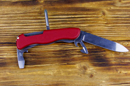 Red all purpose pocket knife on a rustic wooden background. Top viewの写真素材