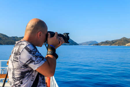 Travel photographer man with professional camera taking photos of the Mediterranean Sea in Antalya...