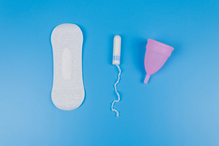Sanitary pad, tampons and menstrual cup on blue background. Top view. Concept of critical days, menstruation, feminine hygieneの写真素材