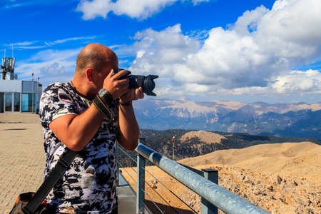 Travel photographer man with professional camera taking photos of on a top of Tahtali mountain near...