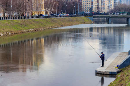 Kharkiv, Ukraine - April 5, 2021: Fisherman with fishing rod standing near the Lopan river in Kharkov, Ukraineのeditorial素材