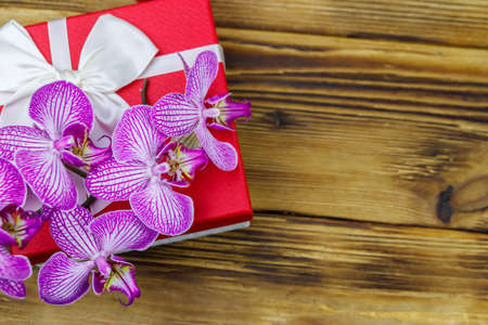Gift box and orchid flower on a wooden background. Top view, copy spaceの写真素材