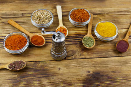Set of different aromatic spices and spice mill on wooden tableの写真素材