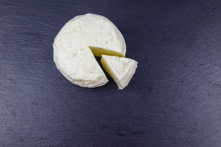 Soft Adyghe cheese on black slate background. Top view