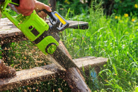 Cutting wood with electric chainsaw at backyardの写真素材