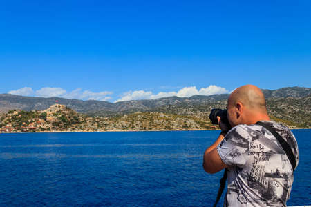 Travel photographer man with professional camera taking photos of the Mediterranean Sea in Antalya province, Turkeyの写真素材