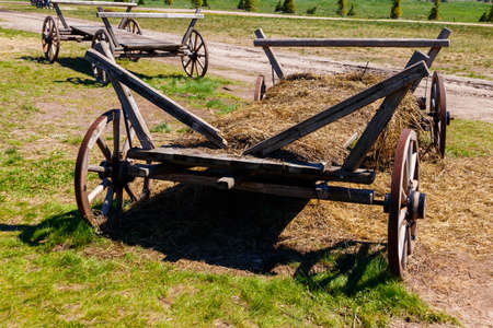 Old wooden cart with hay at farmyardの写真素材