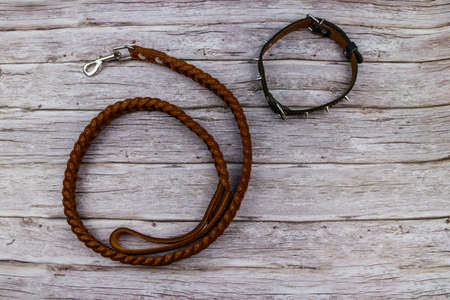 Brown leather leash and spiked collar for dog on wooden background. Top viewの写真素材