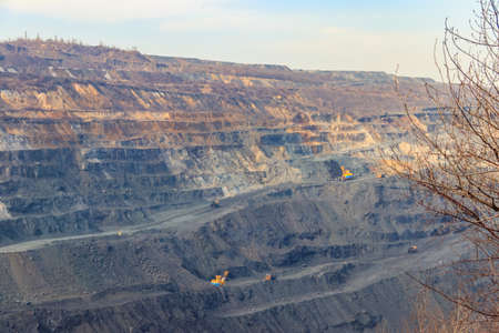 Huge iron ore quarry with working dump trucks and excavators