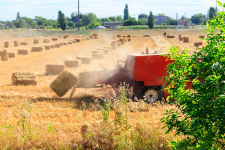 Rectangular baler discharges a straw bale in a field during the harvesting process