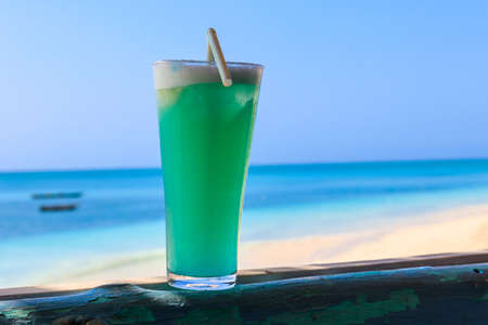 Glass of Blue Hawaii cocktail by the oceanの写真素材