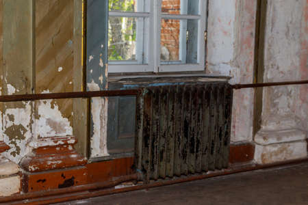 Old cast iron heating battery in a room of abandoned houseの写真素材