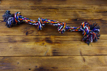 Colorful rope toy for dog on wooden background. Top view