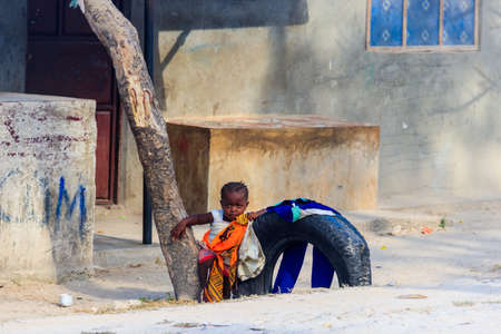 Jambiani, Zanzibar, Tanzania - September 19, 2021: Little African girl next poor house in fishing Jambiani village in Zanzibar, Tanzaniaのeditorial素材